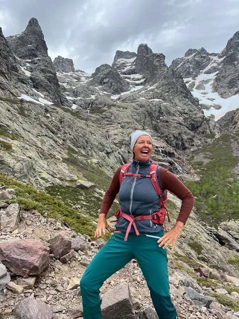 Christina steht lachend in felsigem Hochgebirge